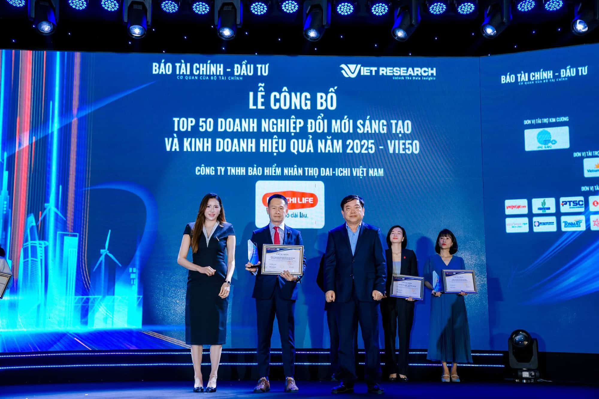 Đại diện Dai-ichi Life Việt Nam nhận giải Top 50 Doanh nghiệp Đổi mới Sáng tạo và Kinh doanh Hiệu quả VIE50 năm 2025 trên sân khấu có màn hình lớn.